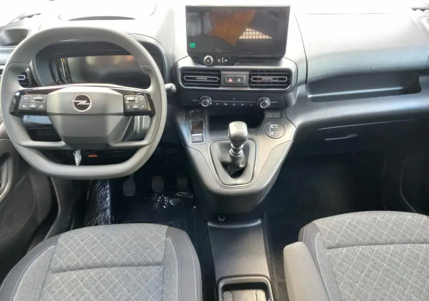Vue intérieure avant de l’Opel Combo Life 2025, tableau de bord noir avec volant multifonction et levier de vitesse manuel.