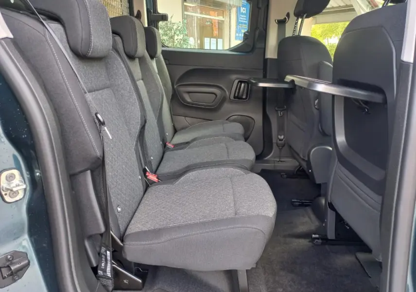 Vue intérieure côté gauche des sièges arrière gris du fourgon Opel Combo Life M 2025, avec tablette rabattable sur le dossier avant.
