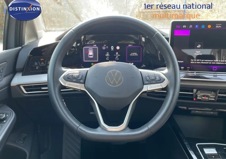 Vue intérieure centrée sur le volant noir et le tableau de bord digital du Volkswagen Golf SW VIII gris lunaire 2024.