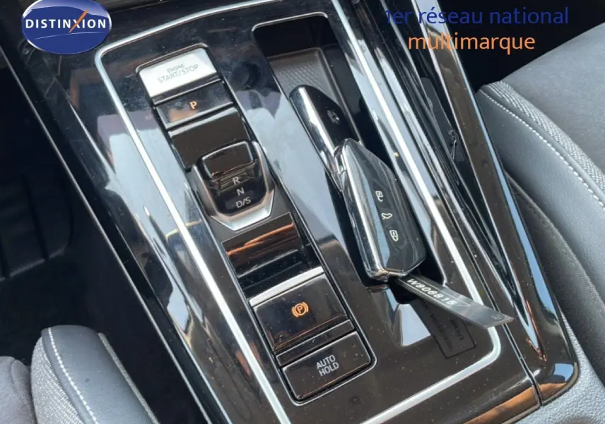 Vue rapprochée de la console centrale noire brillante avec levier de vitesses et bouton start/stop d’une Volkswagen Golf SW gris lunaire.