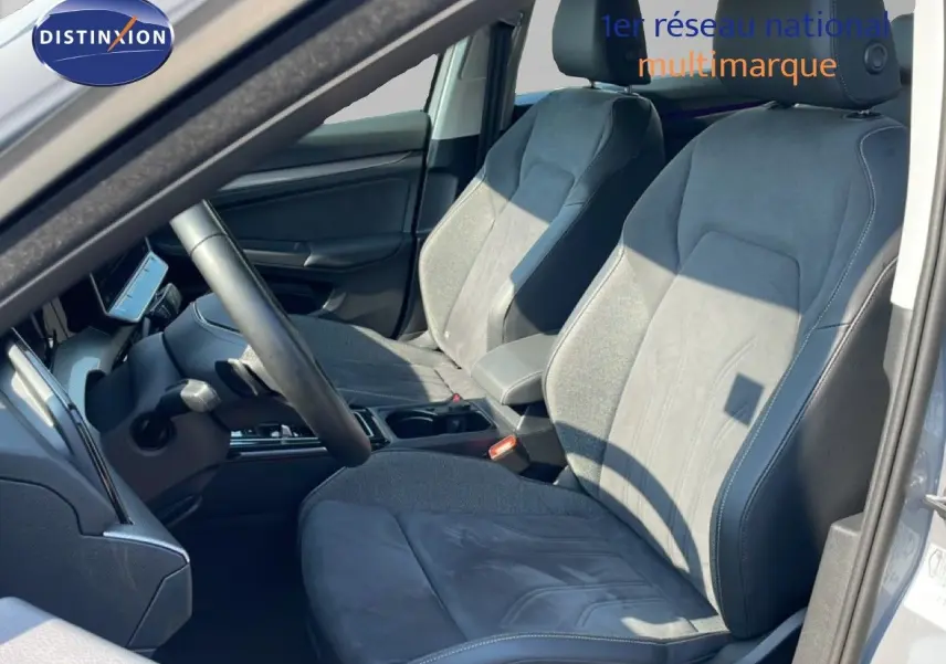 Vue intérieure côté conducteur de la Volkswagen Golf SW VIII gris lunaire, sièges en tissu et cuir gris foncé.