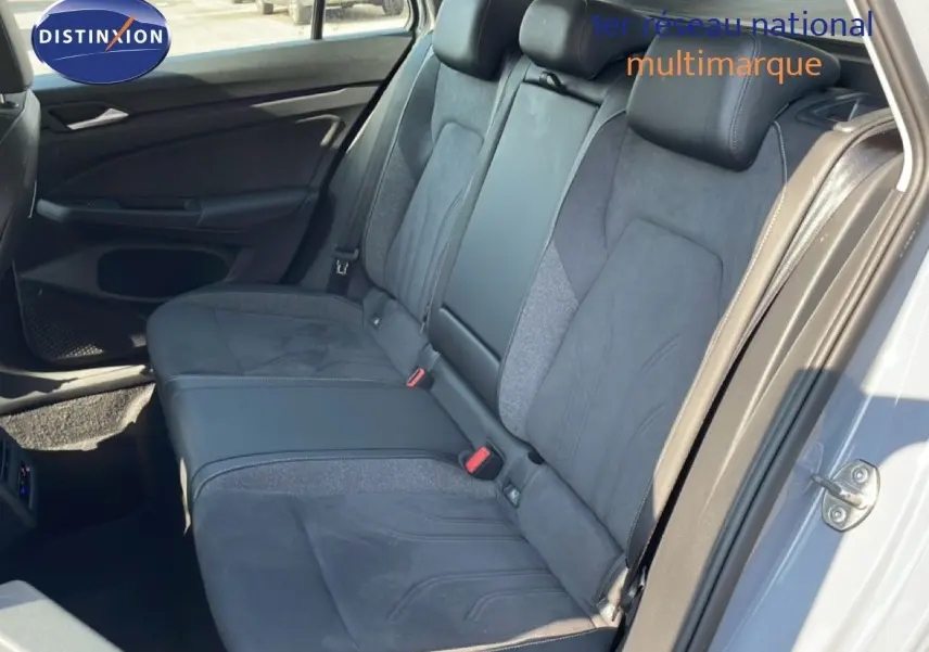 Vue intérieure montrant la banquette arrière en tissu et cuir gris foncé de la Volkswagen Golf SW VIII 2024, porte arrière ouverte.