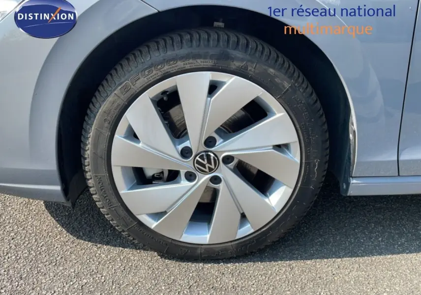 Gros plan sur la roue avant gauche d'une Volkswagen Golf SW VIII gris lunaire métal, jante alliage à cinq branches.