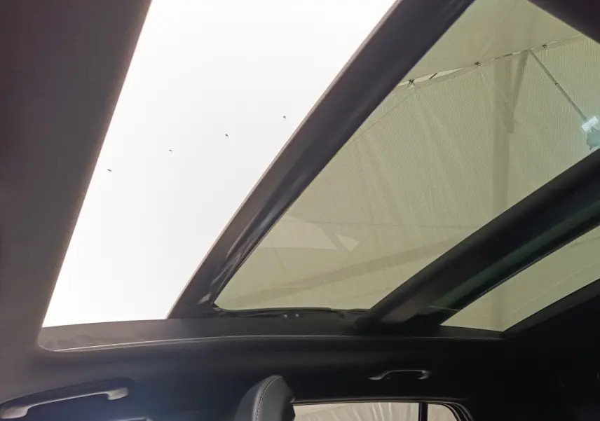Toit ouvrant panoramique en verre du Kia Sportage gris clair, vue intérieure vers le ciel depuis l'arrière.
