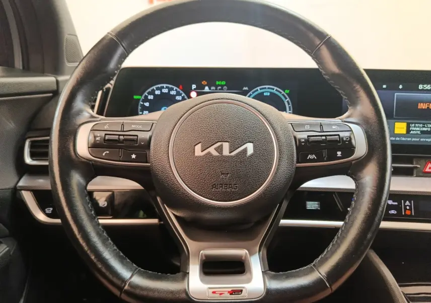 Volant cuir noir avec logo KIA et badge GT-Line, tableau de bord digital lumineux du Kia Sportage gris clair 2022.
