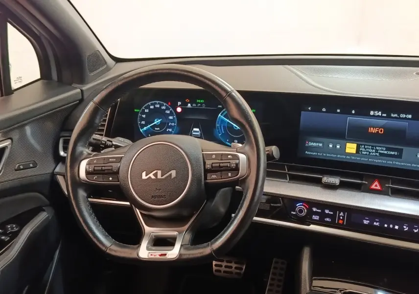 Intérieur du Kia Sportage 2022 vu du poste de conduite, volant cuir GT-Line et tableau de bord numérique lumineux.
