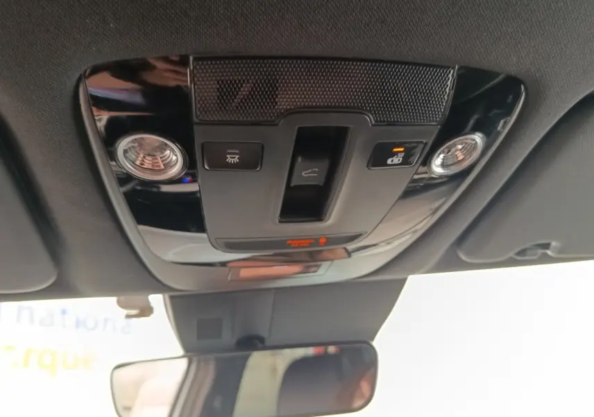 Vue intérieure du plafonnier noir avec commandes d’éclairage et rétroviseur intérieur d’un Kia Sportage gris clair 2022.