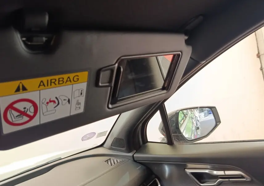Intérieur côté passager du Kia Sportage gris clair 2022, avec miroir pare-soleil ouvert et rétroviseur extérieur visible.
