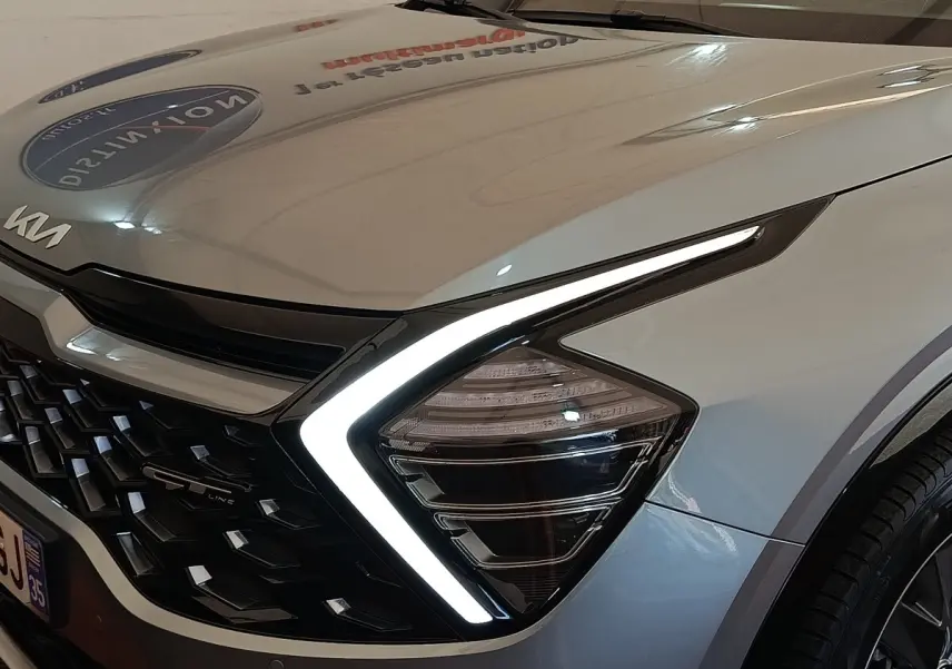 Gros plan sur l’avant droit gris clair du Kia Sportage 2022, avec phares LED en forme de boomerang et calandre noire GT-Line.