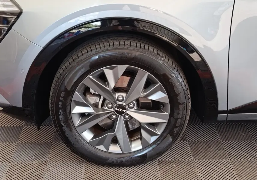 Gros plan sur la roue avant droite gris clair du Kia Sportage 2022 avec jante alliage et logo Kia au centre.