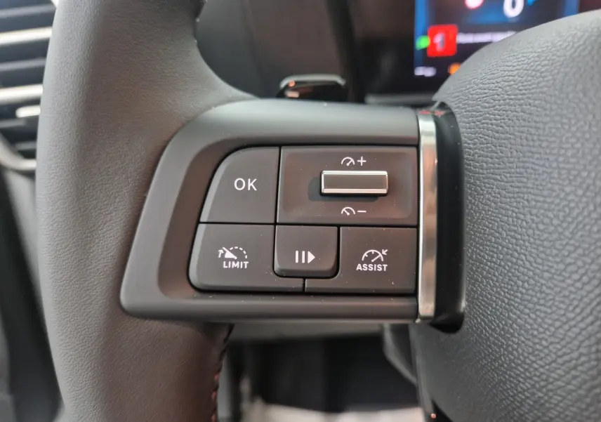 Gros plan sur les commandes au volant côté gauche du Citroën C4 blanc Okenite 2025, boutons de régulateur et assistant de conduite.