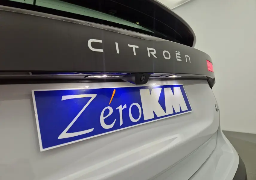 Gros plan arrière sur la malle blanche Okenite d'une Citroën C4 1.2 Hybrid 136 e-DSC6 avec caméra de recul et logo Citroën.