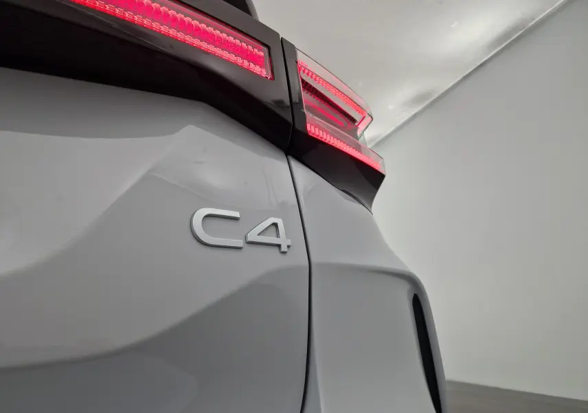 Gros plan sur l'arrière blanc Okenite d'une Citroën C4 2025 avec feux arrière LED allumés et logo C4 visible.