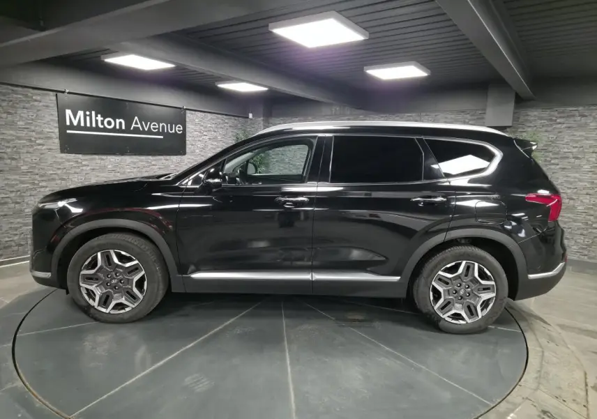 Vue latérale gauche du Hyundai Santa Fé noir 2023 avec jantes alliage et vitres teintées en showroom.
