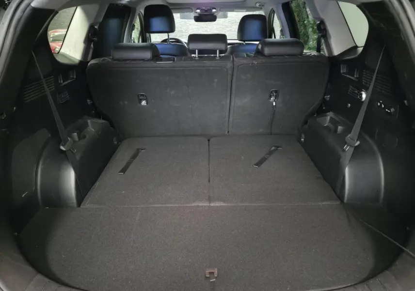 Coffre spacieux du Hyundai Santa Fé 2023 noir avec sièges arrière rabattus et rangements latéraux visibles.