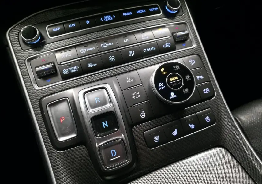 Vue rapprochée de la console centrale noire du Hyundai Santa Fé 2023 avec commandes de climatisation et boîte auto boutons poussoirs.