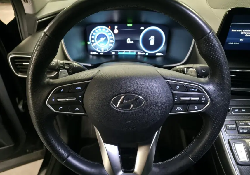Vue rapprochée du volant cuir perforé noir et du tableau de bord numérique du Hyundai Santa Fé 2023 hybride rechargeable.