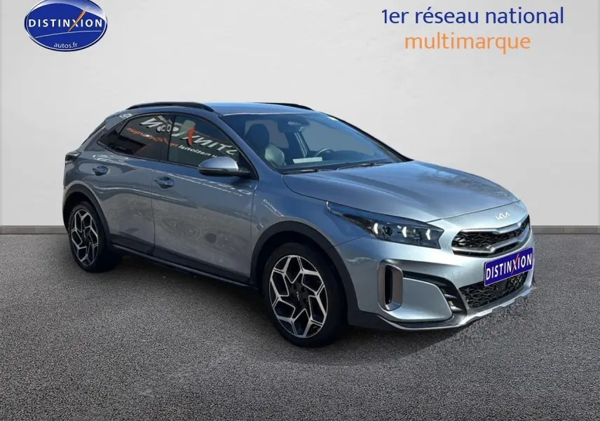 KIA Xceed gris en 3/4 avant droit, avec jantes alu et calandre chromée visible sur fond neutre.