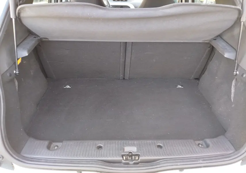 Coffre ouvert vu de l'arrière d'une Renault Twingo blanc cristal 2016, montrant un espace de chargement vide et propre.