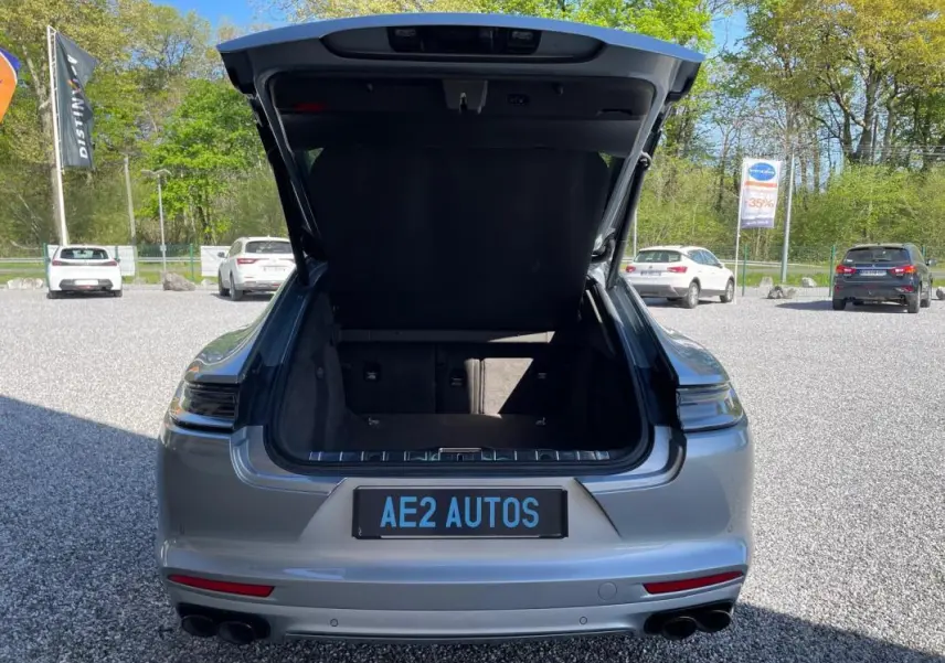 Vue arrière d'une Porsche Panamera 4 V6 3.0 Hybrid gris 2022 avec coffre ouvert et double sortie d'échappement noire.