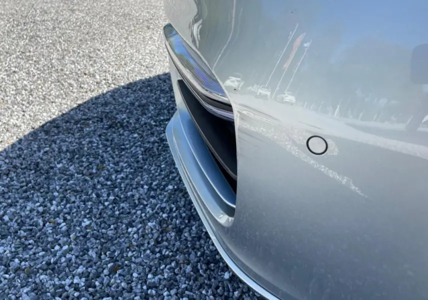 Gros plan sur l'avant droit gris d'une Porsche Panamera 4 V6 Hybrid 2022, mettant en valeur la prise d'air et le capteur de stationnement.