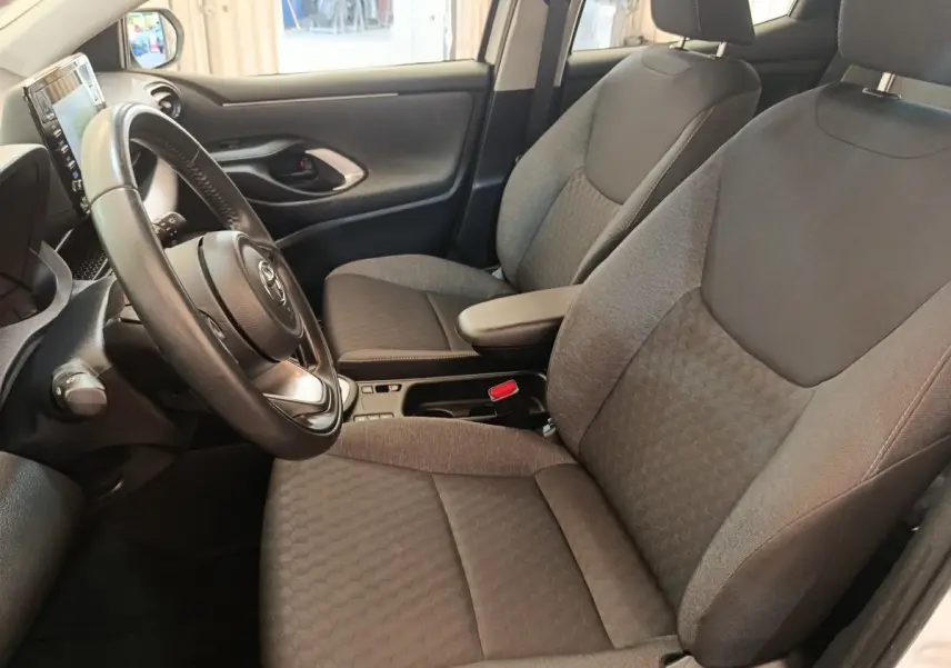 Intérieur de la Toyota Yaris hybride 2022 vu côté conducteur, sièges tissu gris et volant cuir multifonctions.