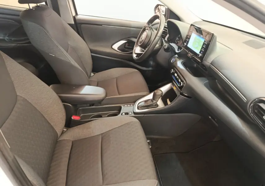 Vue intérieure côté conducteur de la Toyota Yaris hybride 2022, montrant sièges tissu gris et tableau de bord avec écran tactile.