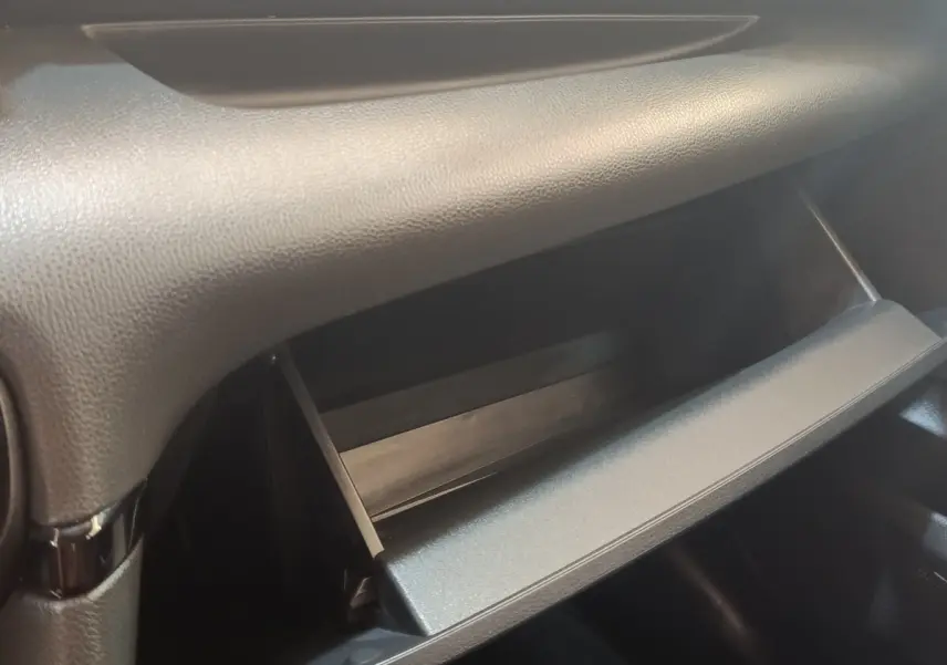 Gros plan sur la boîte à gants ouverte de la Toyota Yaris Hybride 116h Dynamic Business Beyond Zer, intérieur noir.