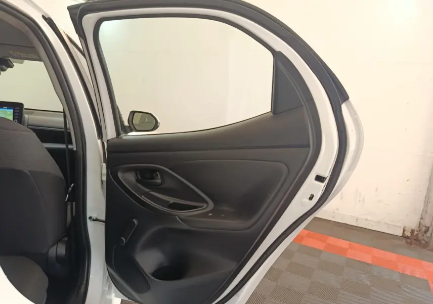 Vue intérieure de la porte arrière droite ouverte d'une Toyota Yaris hybride blanche, montrant la garniture noire.