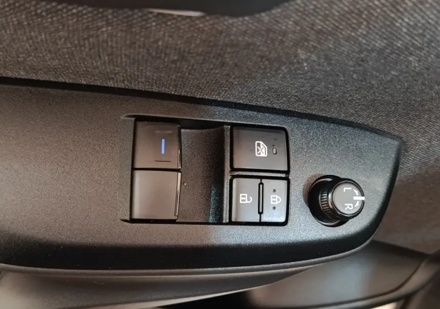 Gros plan sur les commandes de réglage des rétroviseurs et des vitres côté conducteur de la Toyota Yaris blanche hybride 2022.