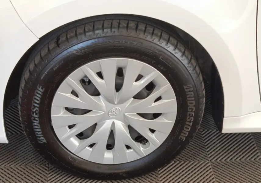 Gros plan sur la roue avant droite blanche d'une Toyota Yaris hybride 2022 avec enjoliveur gris et pneu Bridgestone.