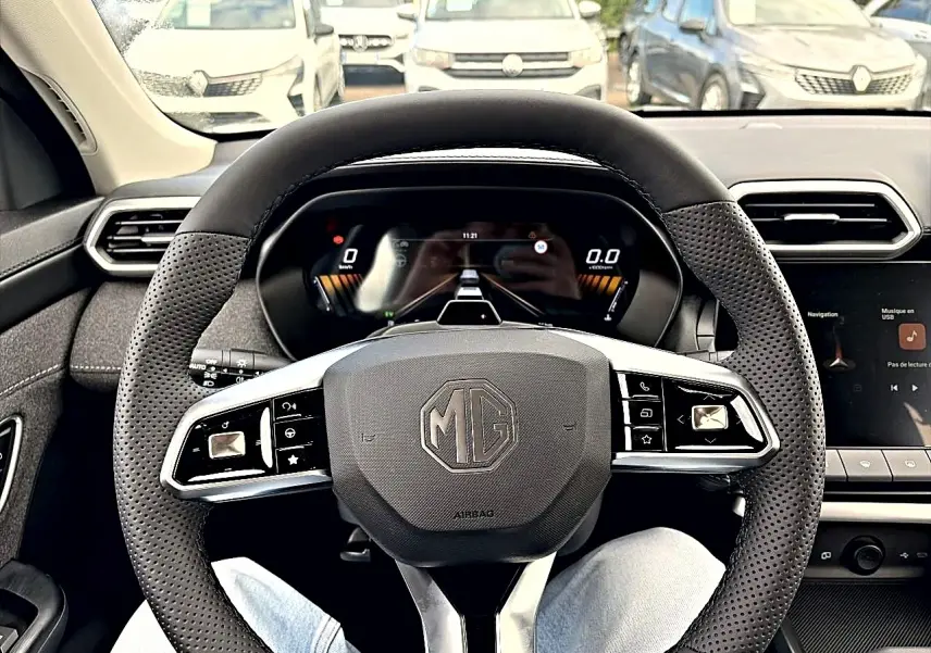 Vue intérieure centrée sur le volant multifonction noir du MG Motor ZS 1.5 hybrid 197, avec tableau de bord digital.
