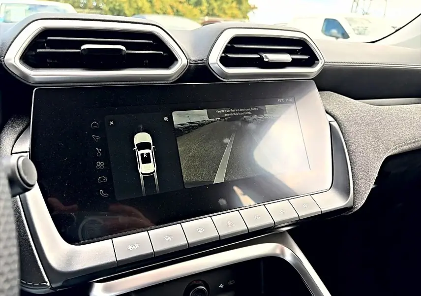 Vue rapprochée de l’écran tactile central et des aérateurs hexagonaux du tableau de bord intérieur du MG Motor ZS Camden grey.