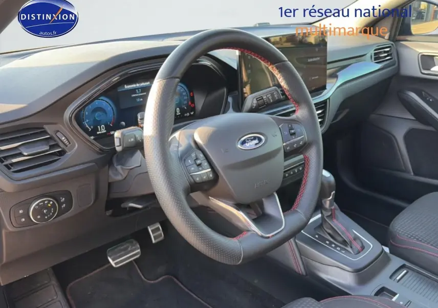 Intérieur avant droit de la Ford Focus noire 2024, volant cuir sport avec surpiqûres rouges et console centrale automatique.