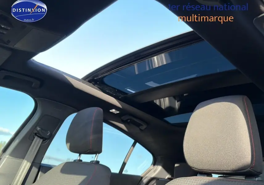 Vue intérieure avant de la Ford Focus noire 2024 avec toit ouvrant panoramique et sièges à surpiqûres rouges.