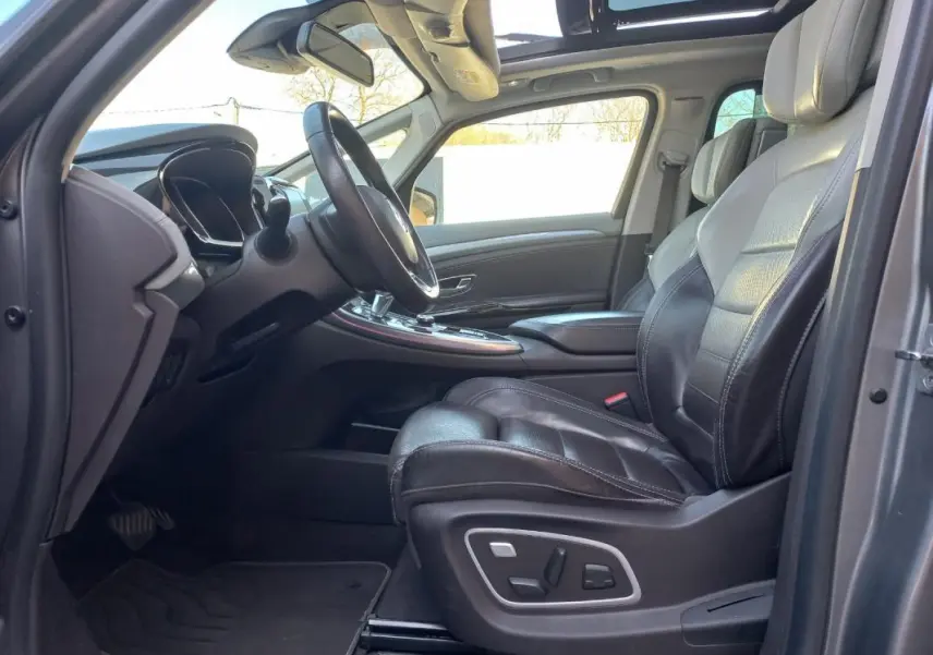 Intérieur côté conducteur du Renault Espace gris 2017, sièges cuir noirs et toit panoramique ouvert.