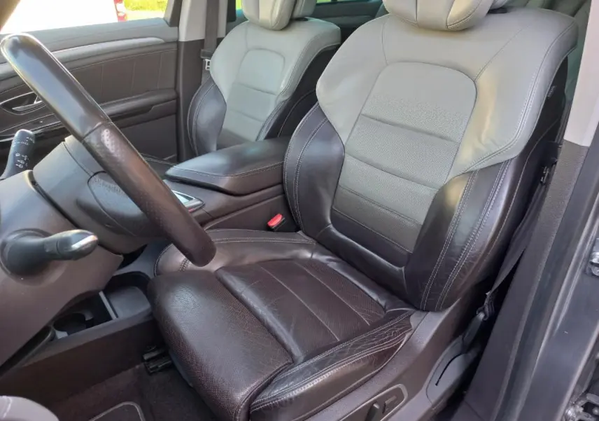 Vue intérieure côté conducteur du Renault Espace gris 2017, siège en cuir bicolore noir et gris avec commandes électriques.