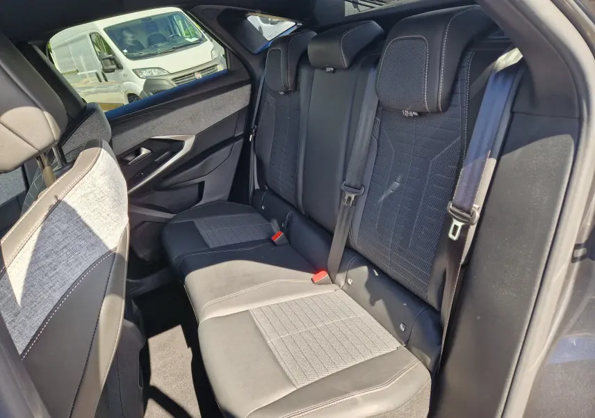 Vue intérieure côté arrière droit du Peugeot 3008 1.2 Hybrid 145 Allure, sièges tissu et cuir gris avec surpiqûres contrastées.