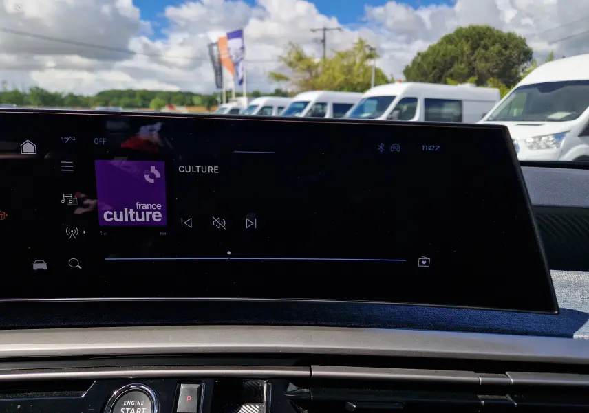 Écran tactile central du Peugeot 3008 2026 gris titane, affichant la radio France Culture en extérieur lumineux.
