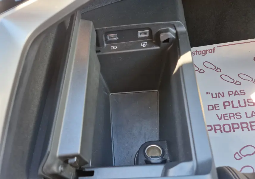 Vue rapprochée de la console centrale ouverte du Peugeot 3008 gris titane, montrant ports USB et prise 12V.