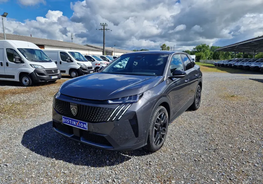 Peugeot 3008 gris titane en 3/4 avant droit sur un parking extérieur, avec calandre noire et jantes noires.