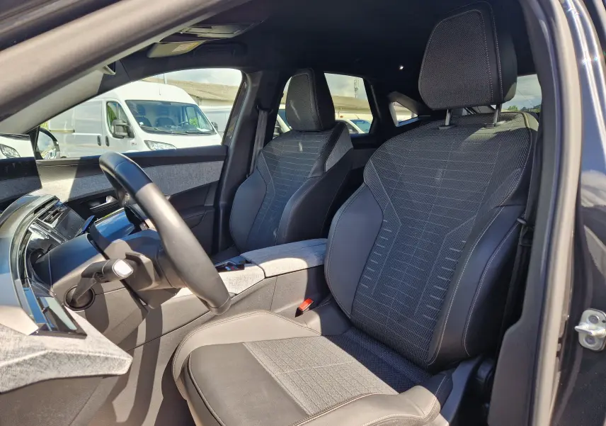 Vue intérieure côté conducteur du Peugeot 3008 gris titane 2026, sièges en tissu et cuir avec détails modernes.