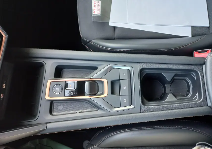 Vue plongeante sur la console centrale noire avec levier de vitesse automatique et surpiqûres cuivrées d'une CUPRA Leon 2025
