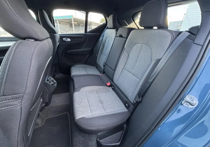 Vue du siège arrière droit du Volvo XC40 Fjord Blue 2024, montrant la sellerie bi-ton grise et noire en tissu et cuir.