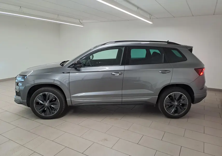 Vue latérale droite d'un Skoda Karoq 2.0 TDI 150 DSG7 Sportline gris graphite métallisé en intérieur, feux arrière allumés.