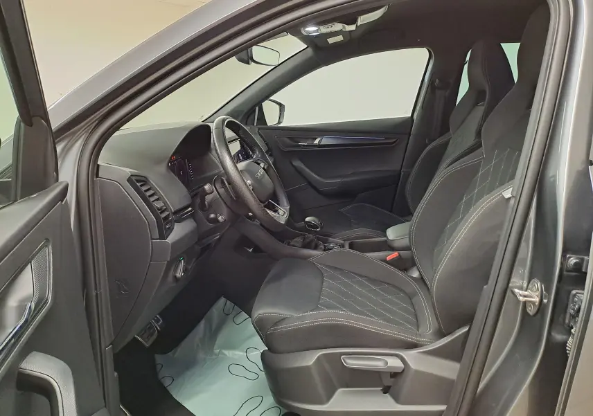 Vue intérieure côté conducteur du Skoda Karoq gris graphite 2025, mettant en valeur les sièges sport et le tableau de bord moderne.