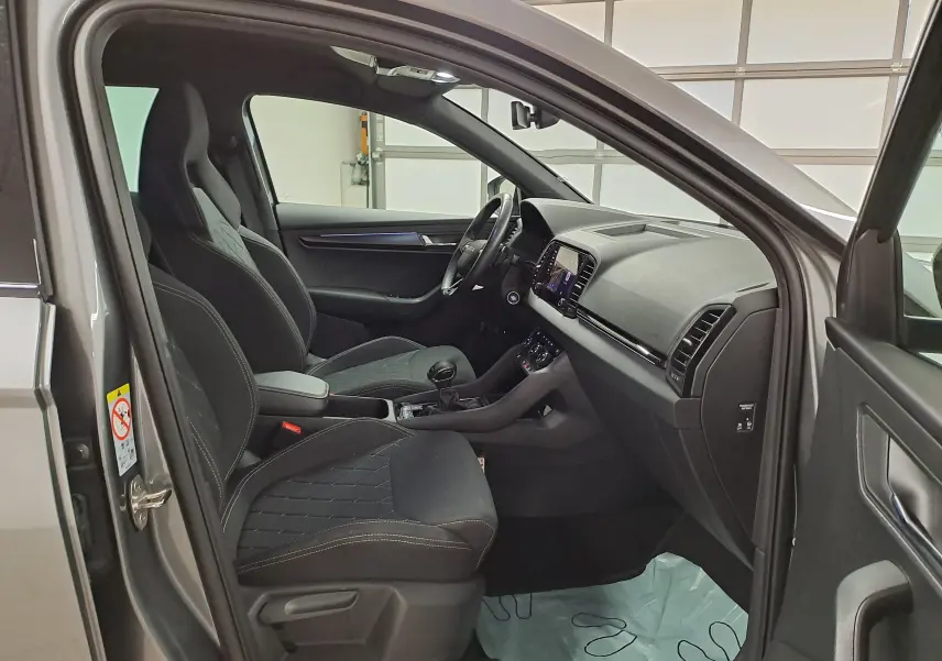 Vue intérieure côté conducteur du Skoda Karoq gris graphite 2025, mettant en valeur les sièges sport et le tableau de bord moderne.