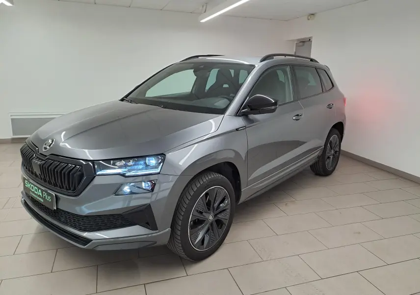Vue 3/4 avant droite du Skoda Karoq gris graphite métallisé avec phares allumés et jantes noires sportline.