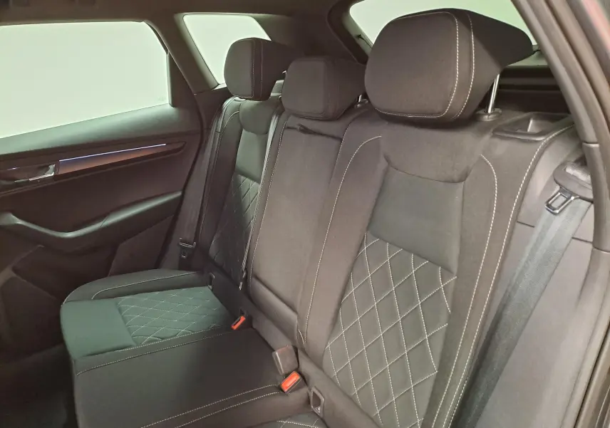 Vue intérieure côté droit des sièges arrière en tissu noir avec surpiqûres blanches du Skoda Karoq 2025 gris graphite.