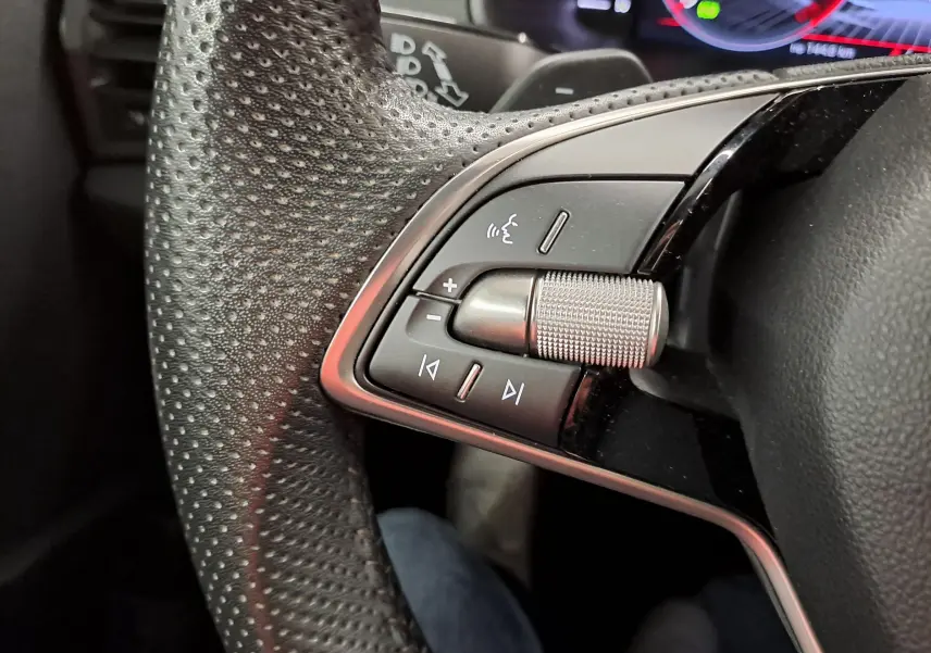 Gros plan sur les commandes multifonctions en métal et cuir perforé du volant du Skoda Karoq gris graphite 2025.